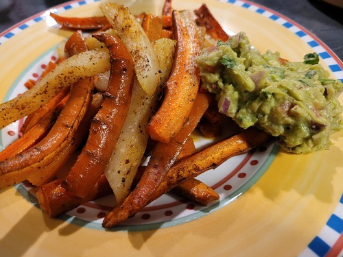 Gemüsesticks aus Karotten und Kohlrabi mit Guacamole auf einem Teller